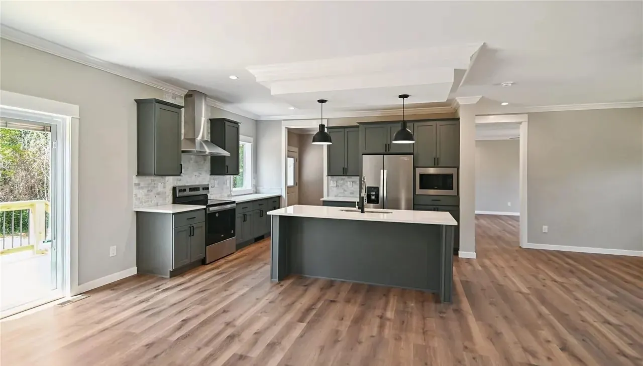Open kitchen with gray cabinets and stainless appliances in a Hart Homes home